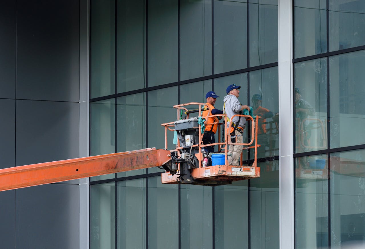 services-04 Two workers clean large glass windows using a cherry picker lift outside a building in Canonsburg, PA.